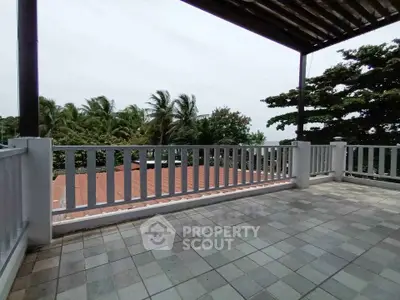 Spacious balcony with scenic view of lush greenery and tiled flooring, perfect for relaxation.
