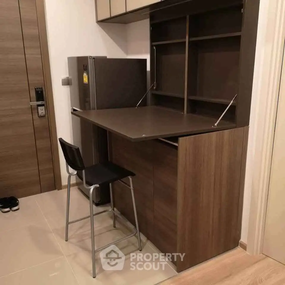 Modern compact kitchen with foldable table and sleek fridge in stylish apartment.