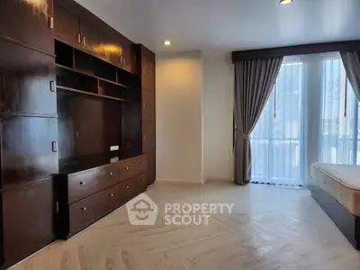 Spacious bedroom with elegant wooden cabinetry and large window for natural light