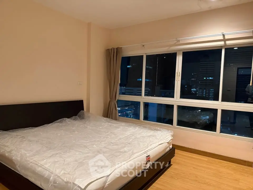 Spacious bedroom with city view and large window, perfect for urban living.