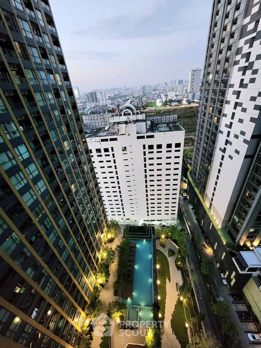 Stunning aerial view of modern high-rise buildings with illuminated pool and cityscape backdrop.