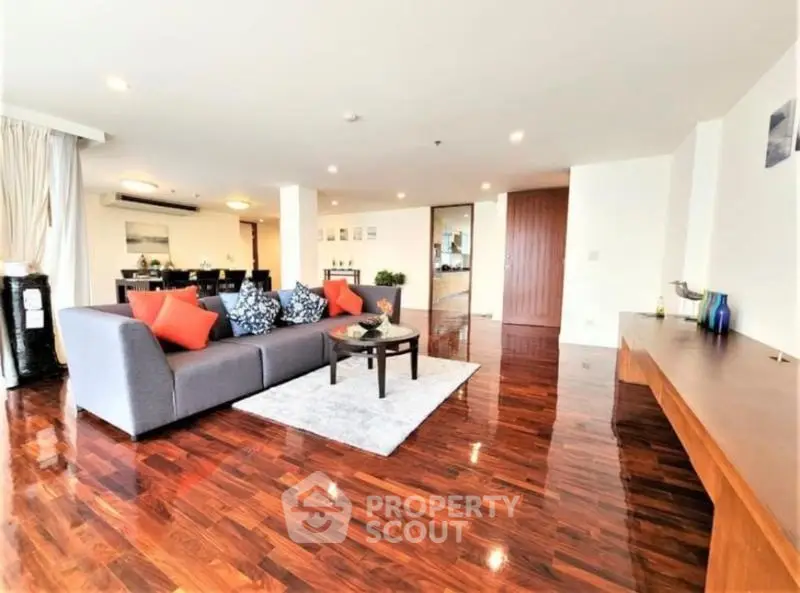 Spacious living room with polished wooden floors and modern decor in luxury apartment.