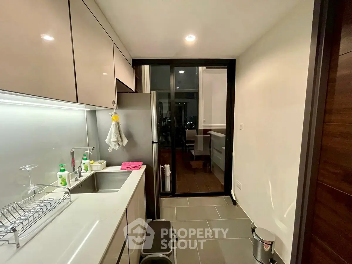 Modern kitchen with sleek cabinetry and stainless steel appliances in a cozy apartment.