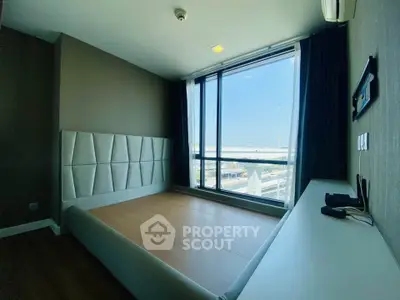Spacious bedroom with large window offering stunning city view, modern design and ample natural light.