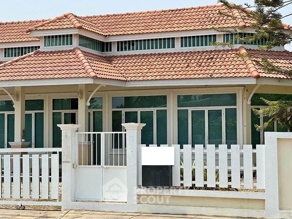 Charming suburban house with red-tiled roof and white picket fence