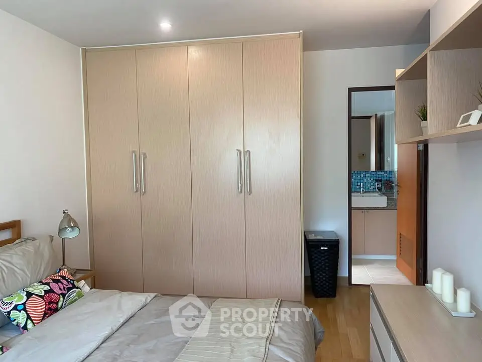 Cozy bedroom with built-in wardrobe and view into modern bathroom