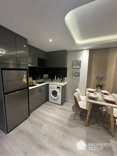 Modern kitchen with sleek grey cabinets, integrated appliances, and elegant dining area with stylish decor.