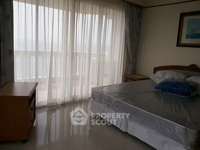 Spacious bedroom with balcony and ocean view, featuring elegant curtains and polished flooring.