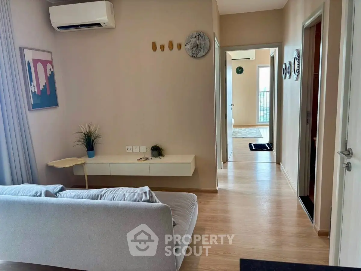 Modern living room with sleek design and air conditioning, featuring light wood flooring and contemporary decor.