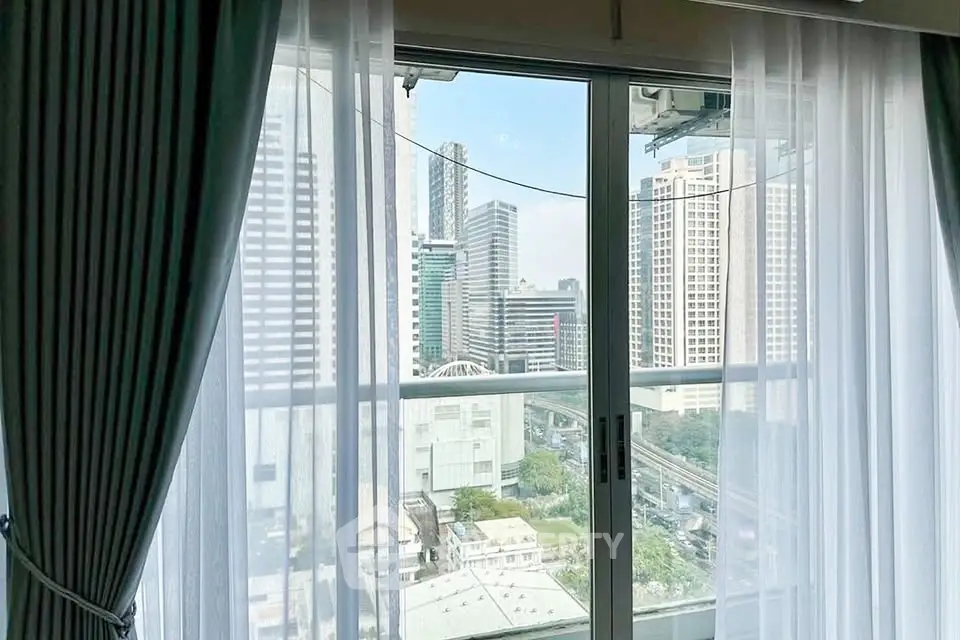 Stunning cityscape view from a high-rise apartment window with elegant curtains.