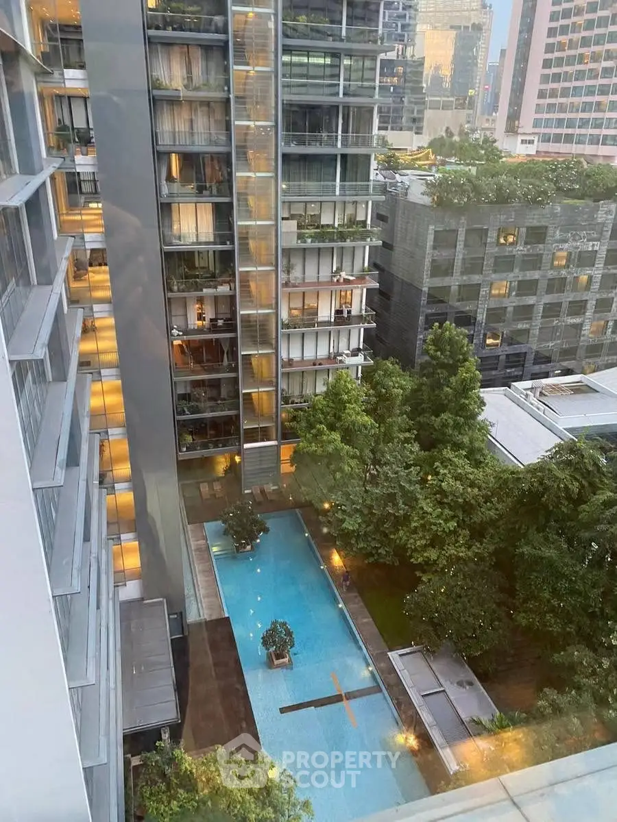 Stunning high-rise view with luxurious pool and lush greenery in urban setting.