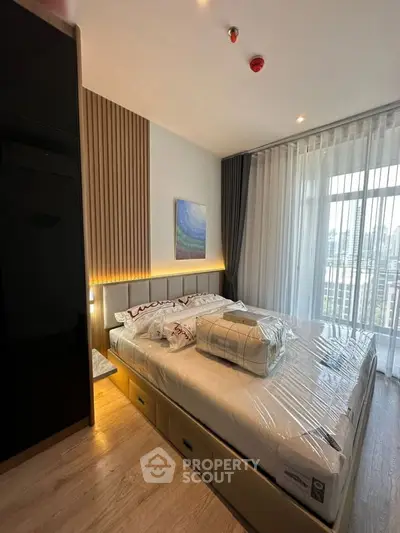 Modern bedroom with large window and city view, featuring stylish decor and ample natural light.