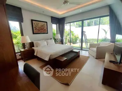 Luxurious bedroom with garden view and modern decor, featuring large windows and elegant furnishings.