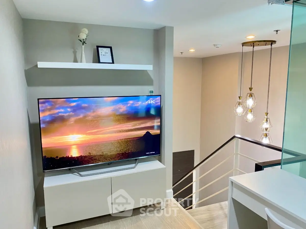 Modern living room with stylish decor and large TV, featuring elegant lighting and sleek design.