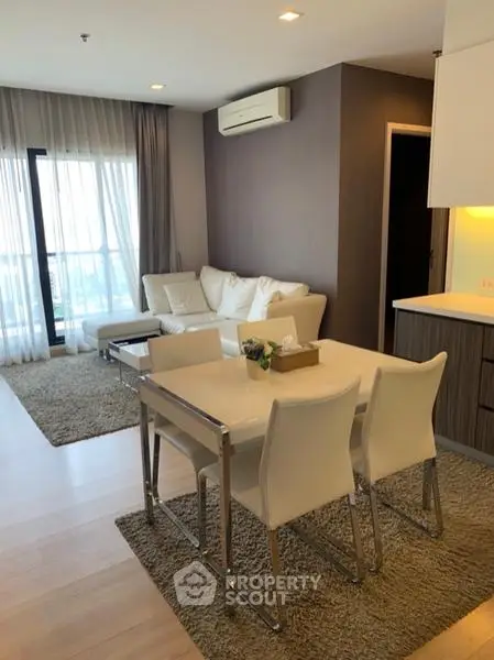 Modern living room with elegant dining area and large windows in a stylish apartment.