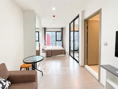 Modern open-plan apartment with bedroom and living area, featuring large windows and stylish decor.