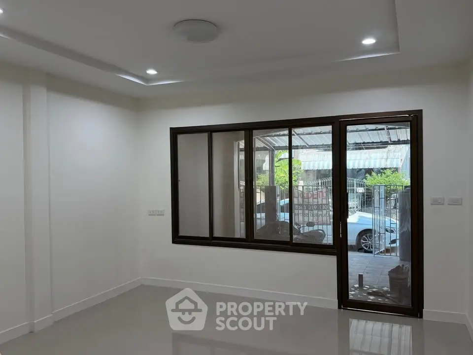 Spacious living room with large window and modern lighting, perfect for natural light and comfort.