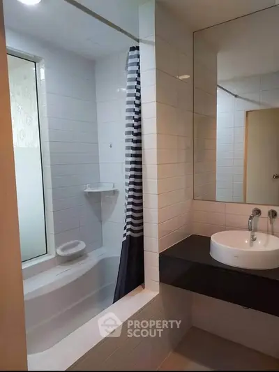Modern bathroom with sleek design featuring a bathtub and stylish sink area.