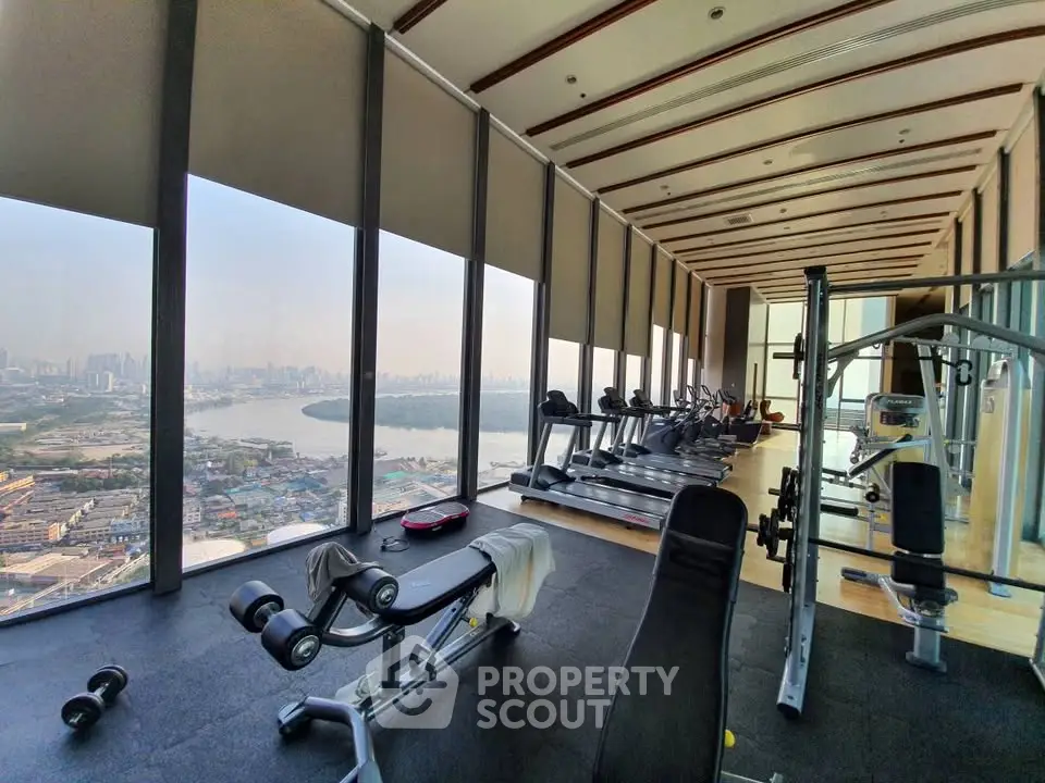 Luxurious high-rise gym with panoramic city and river views, featuring modern fitness equipment and floor-to-ceiling windows.