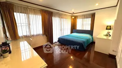 Spacious bedroom with large windows and elegant wooden flooring