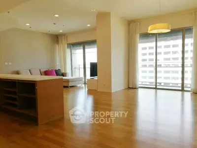 Spacious modern living room with hardwood floors and large windows offering city views.