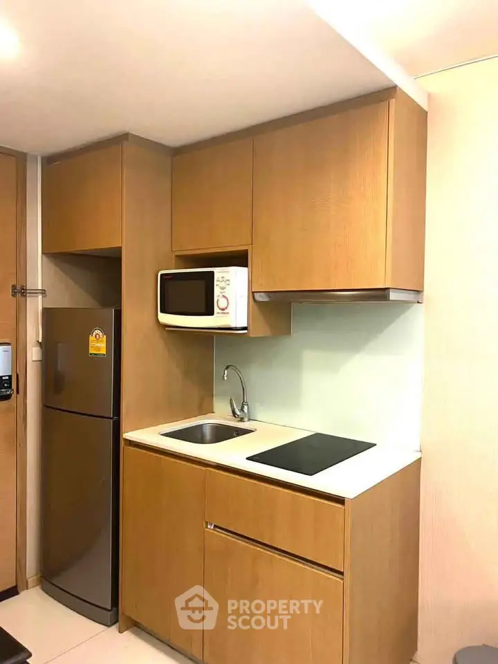 Modern compact kitchen with wooden cabinets and built-in appliances