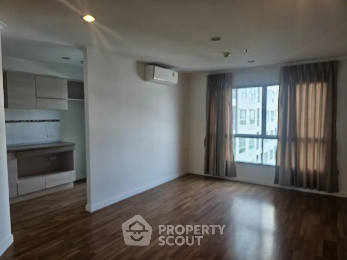 Spacious unfurnished living room with wooden flooring and large window in modern apartment.