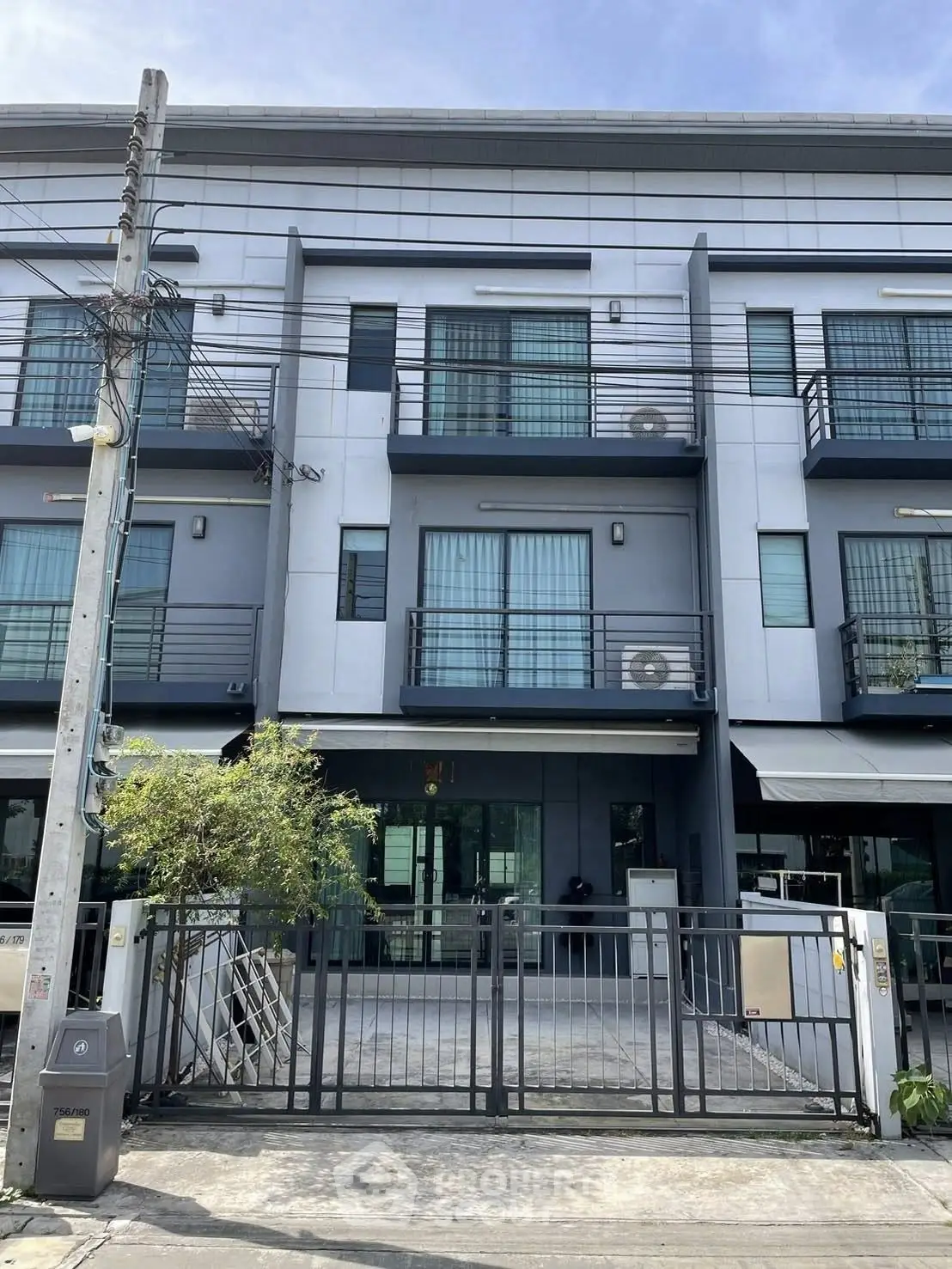 Modern three-story townhouse with sleek design and gated entrance, perfect for urban living.