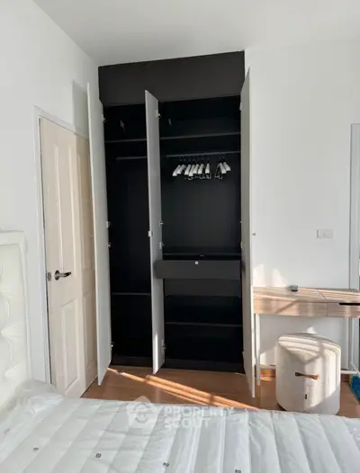 Modern bedroom with open wardrobe and stylish furniture, showcasing contemporary design and functionality.