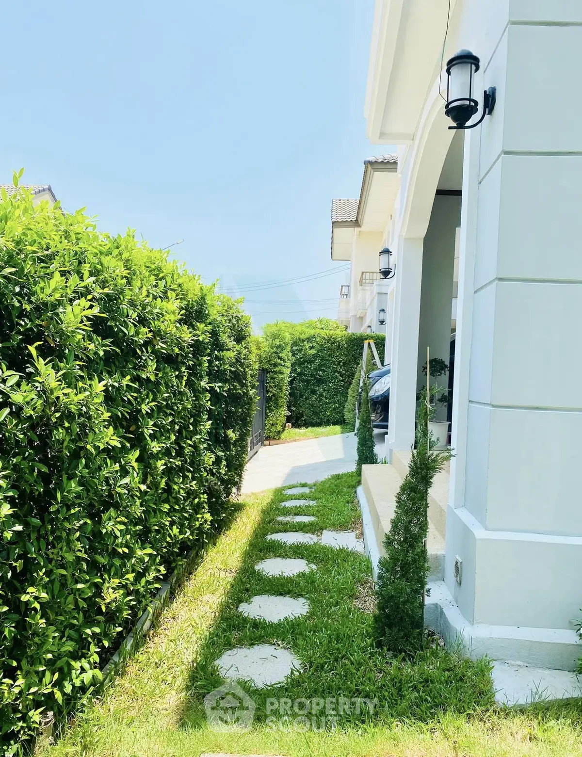 Charming garden pathway leading to a modern home entrance with lush greenery.