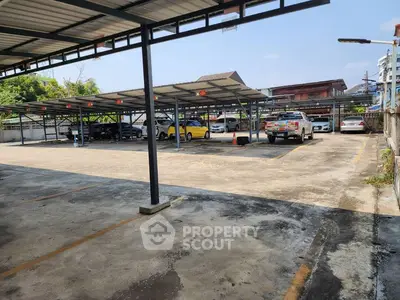 Spacious covered parking area with multiple vehicles and clear sky view.