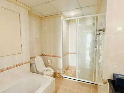 Spacious bathroom with bathtub and glass shower enclosure in modern apartment.