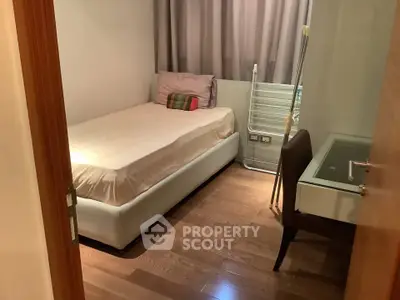 Cozy bedroom with wooden flooring and modern furnishings in a compact layout.