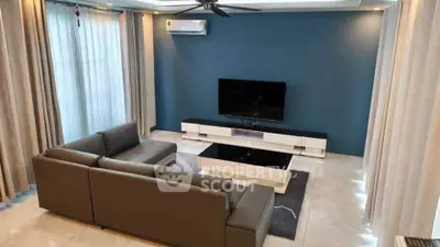 Modern living room with sleek furniture and large TV, featuring elegant curtains and a ceiling fan.