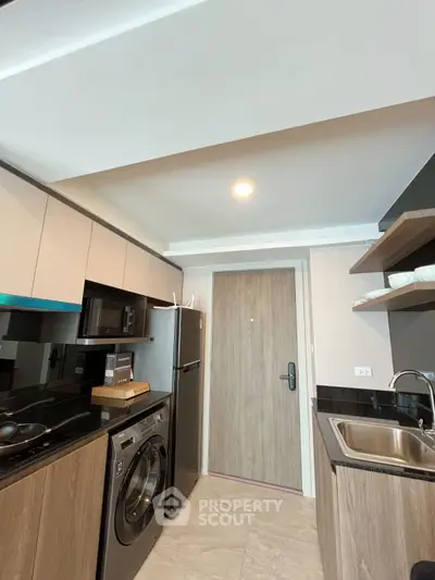 Modern kitchen with sleek appliances and washing machine in compact layout
