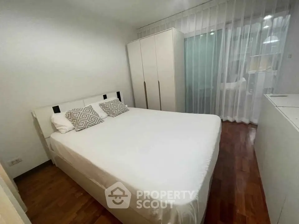 Cozy bedroom with modern furnishings and wooden flooring, featuring a comfortable bed and ample storage space.
