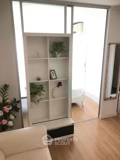 Modern living room with stylish shelving and indoor plants, featuring sleek wooden flooring and natural light.