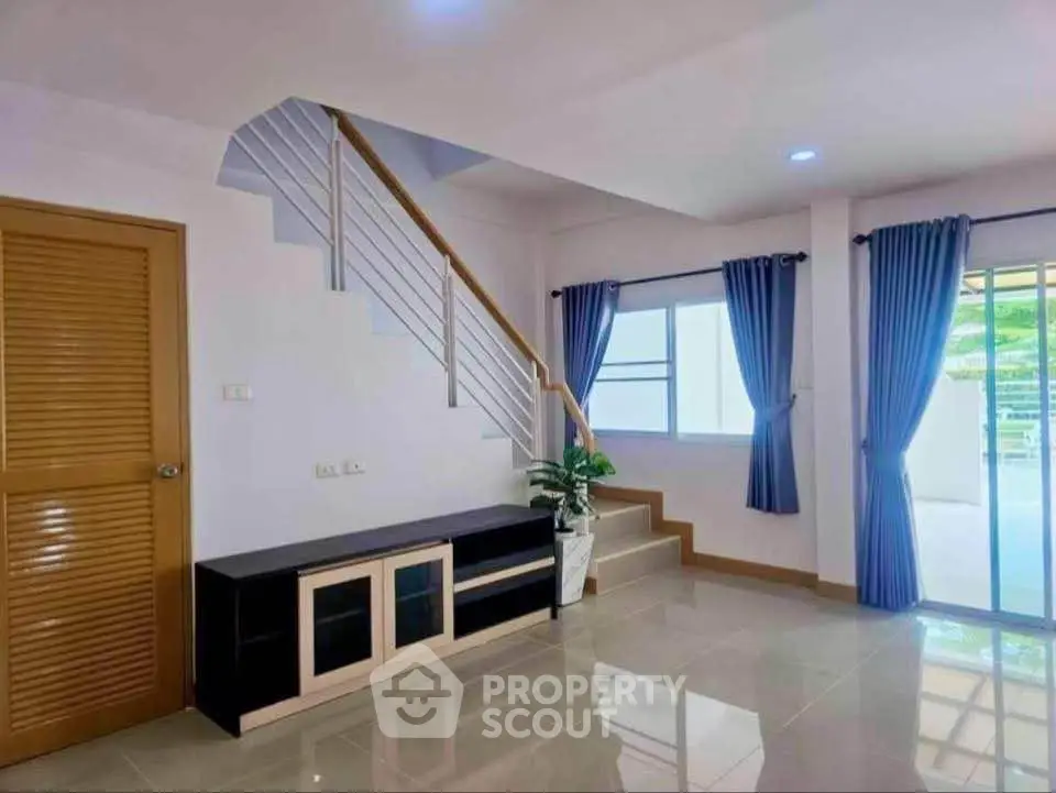 Spacious modern living room with staircase and large windows for natural light.