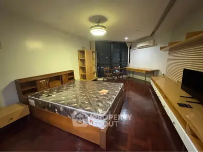 Spacious bedroom with wooden flooring and modern furnishings in a cozy apartment.