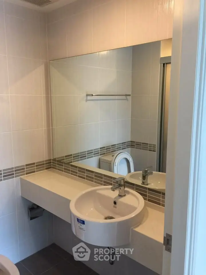 Modern bathroom with sleek sink and large mirror in a stylish apartment.