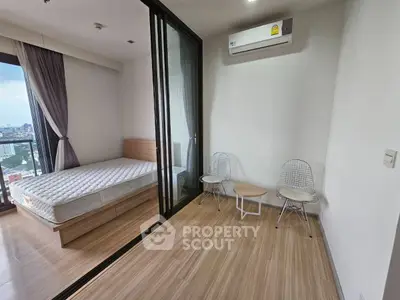 Modern bedroom with balcony view and minimalist furniture in urban apartment.