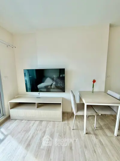 Modern living room with sleek TV and dining area, featuring light wood flooring and minimalist decor.