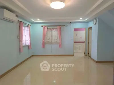 Spacious living room with pastel walls and tiled flooring, featuring large windows and modern lighting.