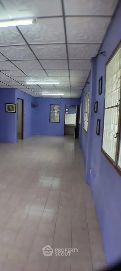 Spacious interior with purple walls and tiled flooring, featuring large windows for natural light.