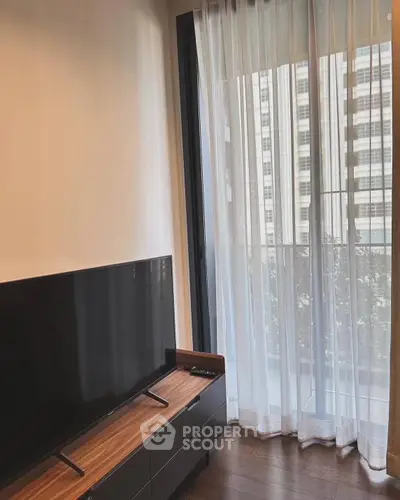 Modern living room with sleek TV stand and large window offering city view.