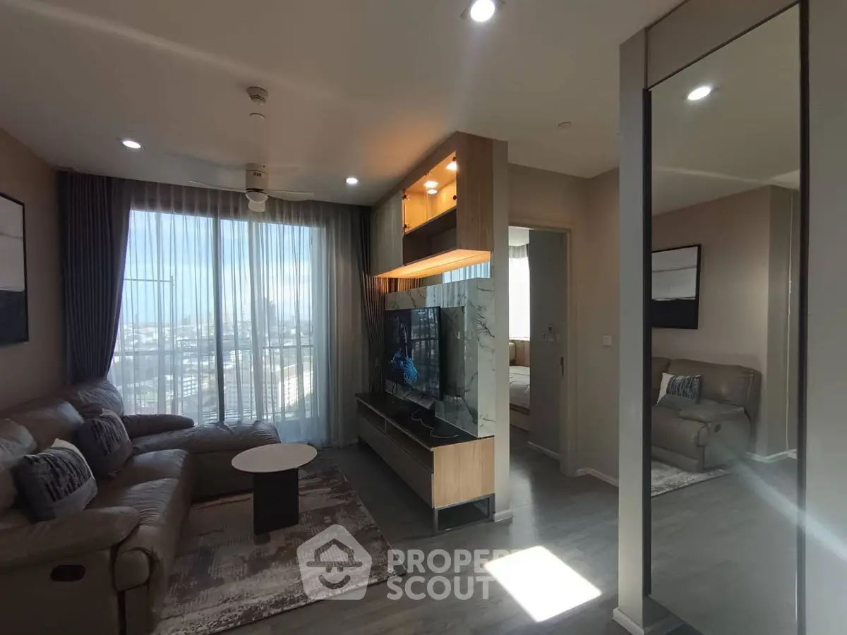 Modern living room with large windows and stylish furniture in a high-rise apartment.