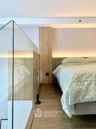 Modern bedroom with glass railing and stylish bedding in a contemporary home.