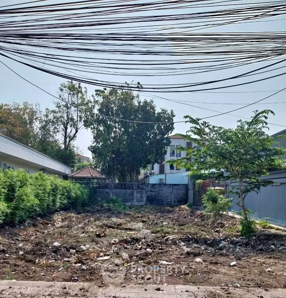 Vacant land plot with potential for development in a residential area, surrounded by greenery and neighboring houses.