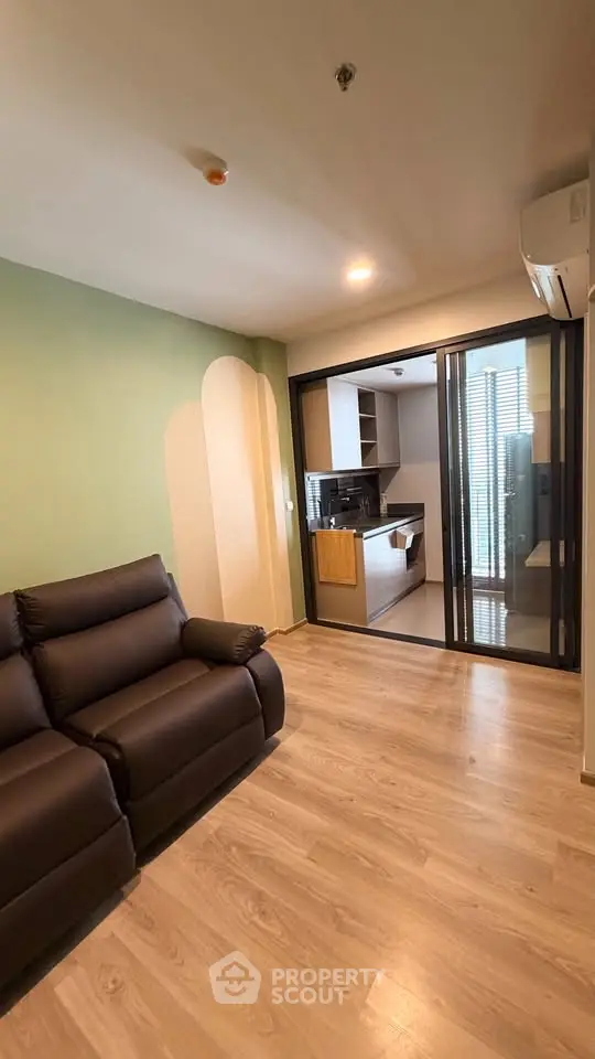 Modern living room with sleek design and open kitchen layout, featuring stylish flooring and comfortable seating.