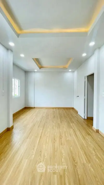 Spacious empty room with wooden flooring and modern ceiling lights, perfect for customization.